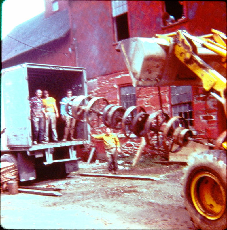 Picture 8 - Unloading the line shaft which powered the roller mills from the tractor trailer September 29, 1974.  Years later the historical society gave this away for scrap iron.